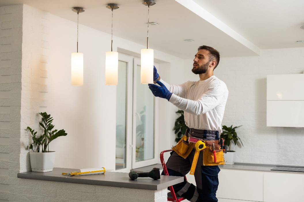Ein Elektriker montiert Lampen und Strahler im Loft-Stil an der Decke.